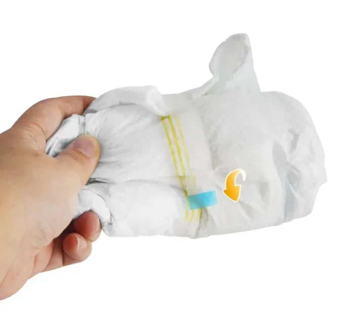 Kamay na may hawak na naka-roll-up na Q-shape na Baby Pants diaper na may dilaw na icon na arrow.