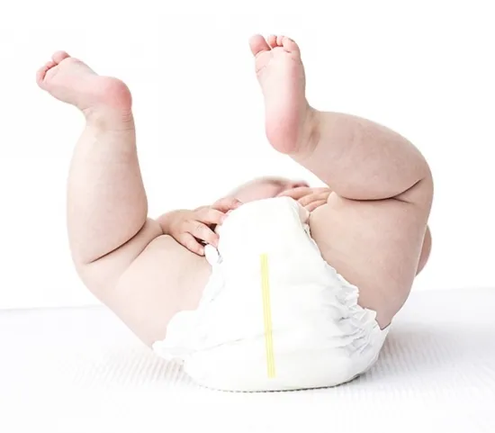 Sanggol na nakasuot ng ultra-wide waistband diaper, mapaglarong sinisipa ang mga binti sa puting background.