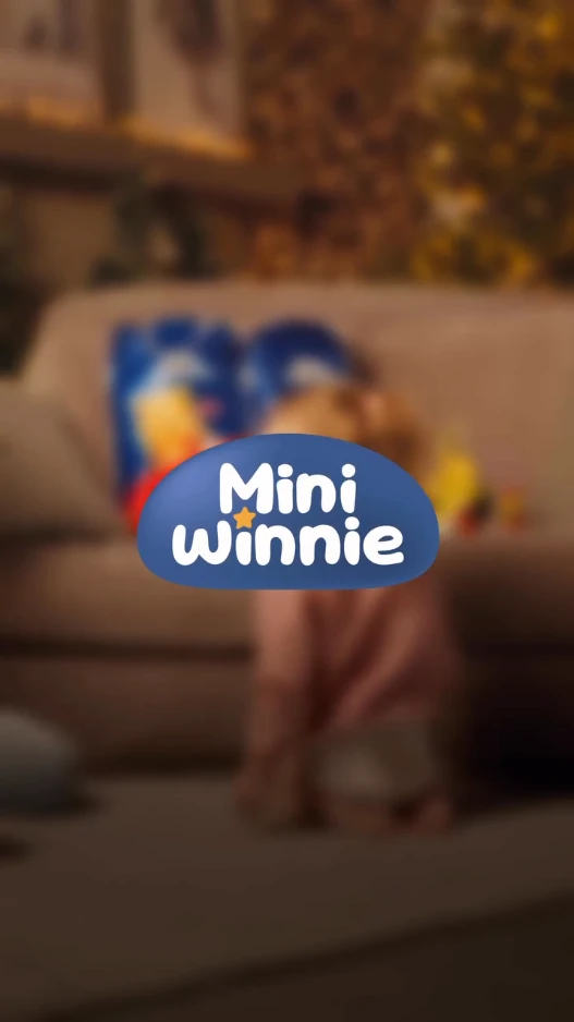 Malabong bata at mga laruan sa isang sopa na may logo ng Mini Winnie sa harapan.