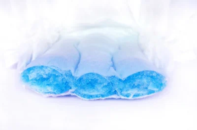 Close-up ng isang cut diaper na nagpapakita ng sumisipsip na asul na mga layer ng gel sa loob.